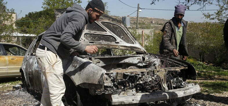 פלסטינים בכפר ג'אלוד בוחנים את רכבם שהוצת על ידי פלסטינים, מרס 2022 (צילום: רויטרס)