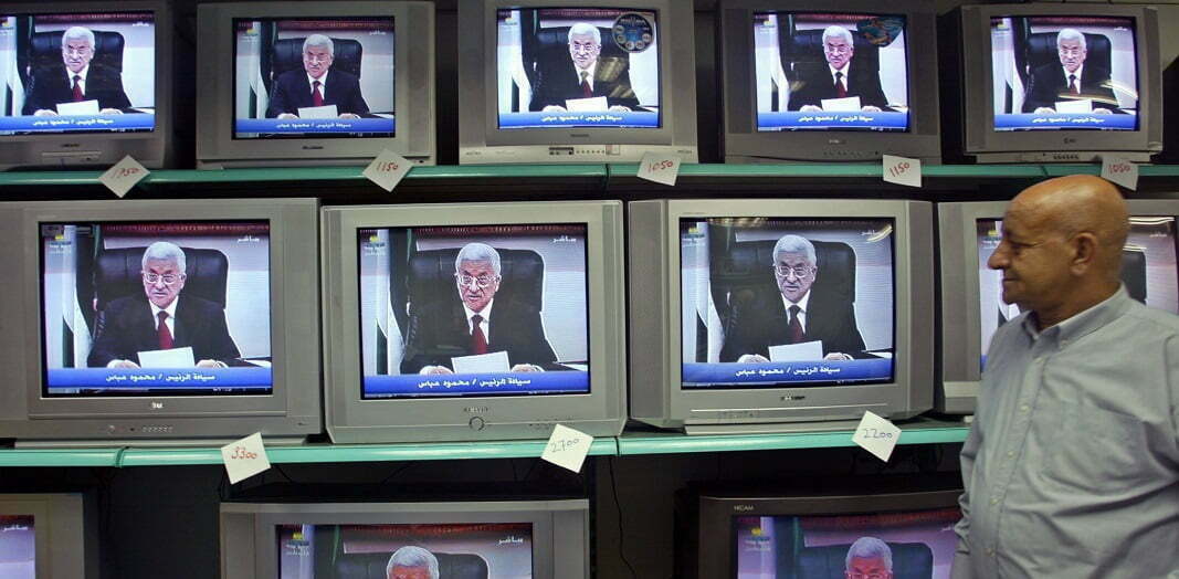 פלסטיני צופה בטלוויזיה בנאום של עבאס, בעזה, 2005. צילום: רויטרס