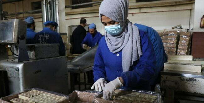 אישה פלסטינית במפעל לשוקולד ולביסקוויטים בדיר אל־בלח, 2022. צילום: רויטרס