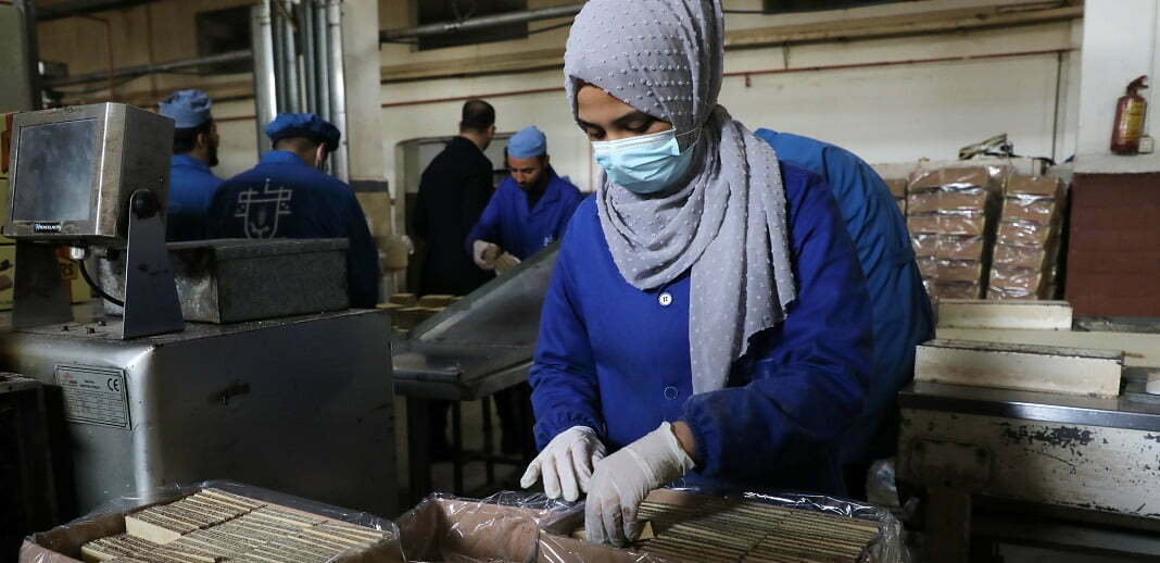 אישה פלסטינית במפעל לשוקולד ולביסקוויטים בדיר אל־בלח, 2022. צילום: רויטרס